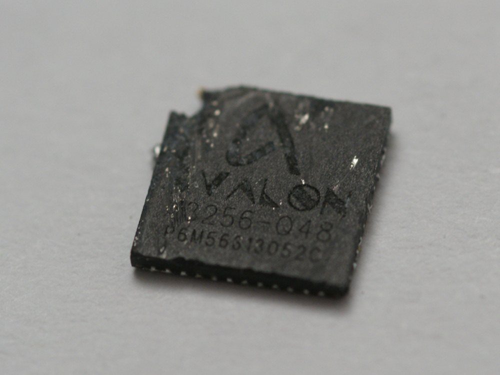 Primer plano de un chip negro de minería de bitcoin sobre una superficie gris, con la serigrafía parcialmente legible