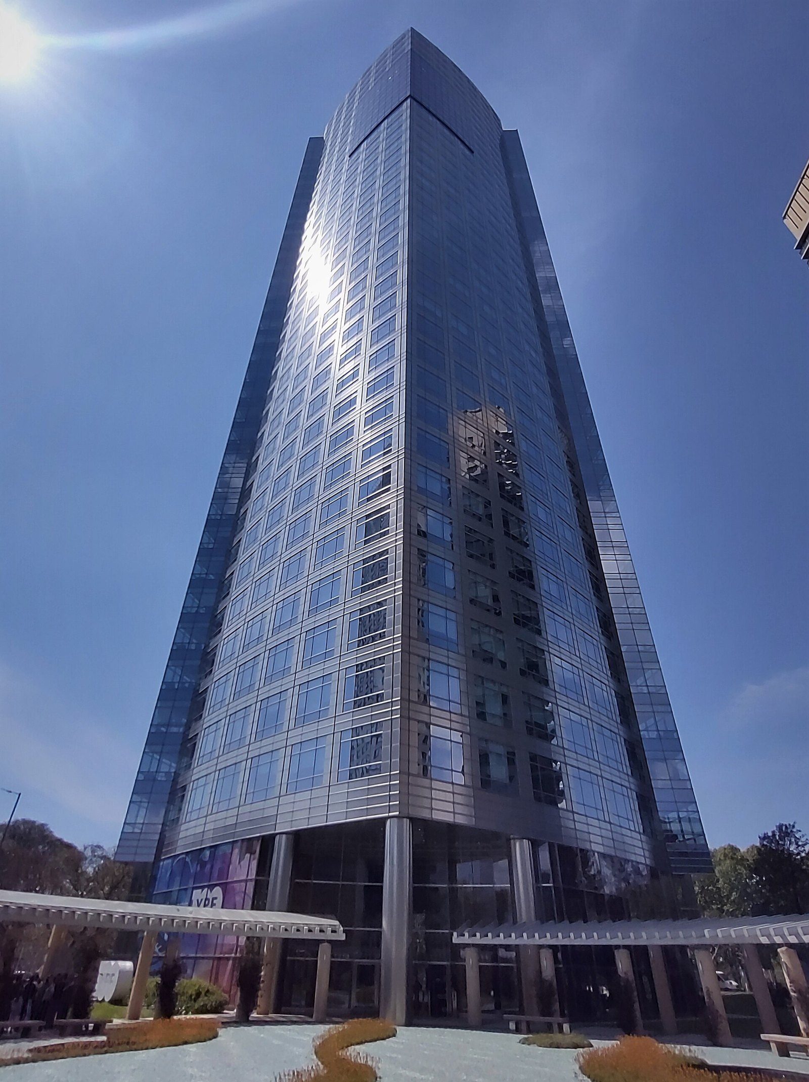 Torre YPF, edificio de vidrio de gran altura visto desde su base, con cielo azul despejado, en Puerto Madero, Buenos Aires